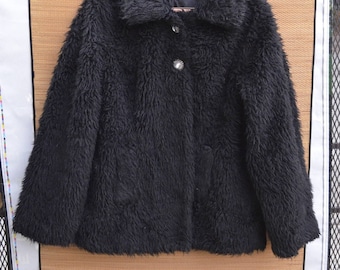 May include: A black fuzzy jacket with a button closure and a single pocket on the left side.