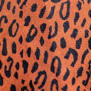 May include: Orange fabric with a black leopard print pattern.