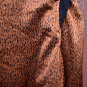 May include: A brown and black patterned fabric with a black trim. The fabric has a subtle sheen and a soft texture.