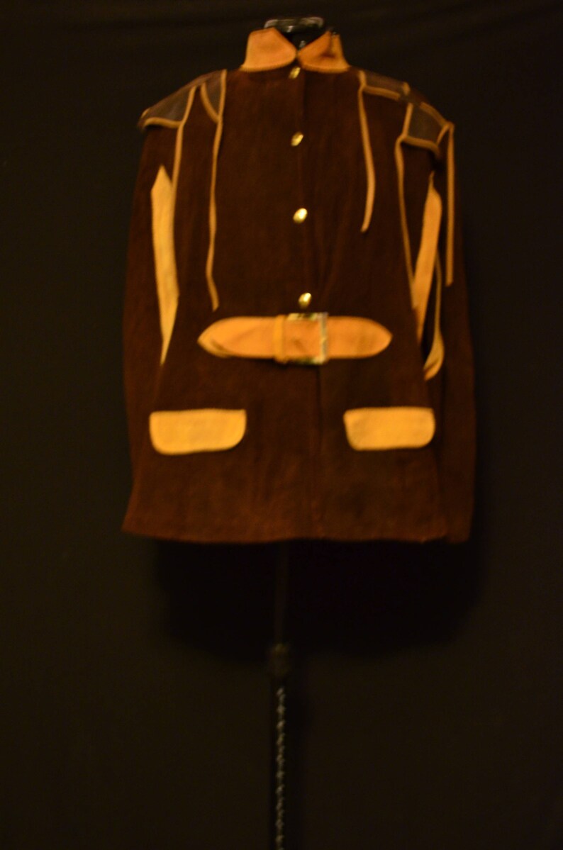 May include: A brown suede jacket with a tan leather trim and a belt. The jacket has a stand-up collar and a button closure.