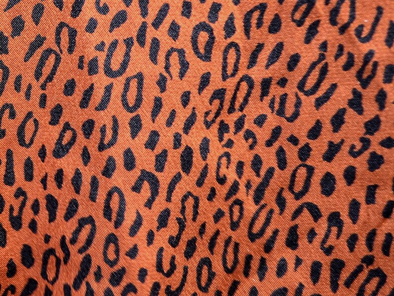 May include: Orange fabric with a black leopard print pattern.
