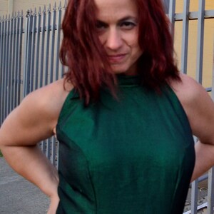 May include: A woman with long red hair wearing a green halter top.