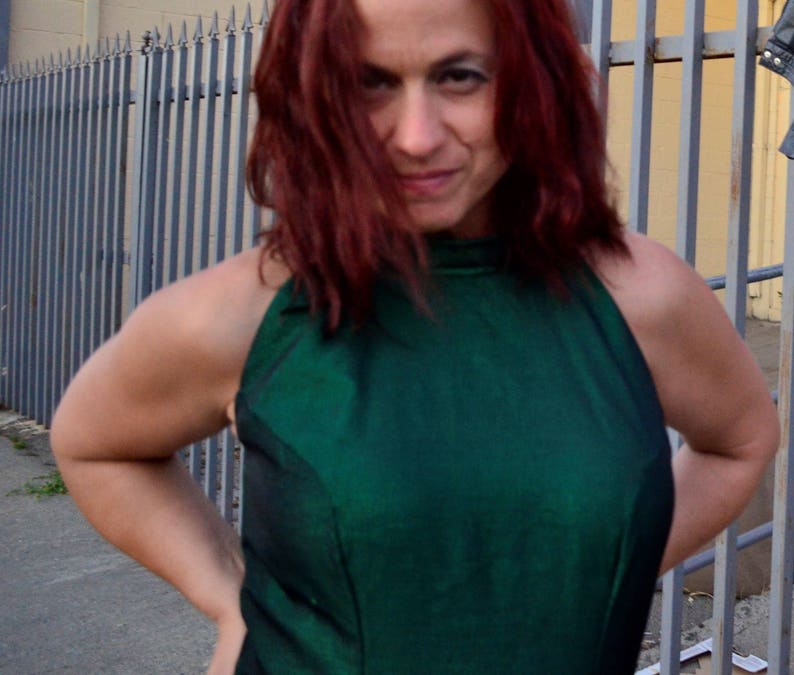 May include: A woman with long red hair wearing a green halter top.