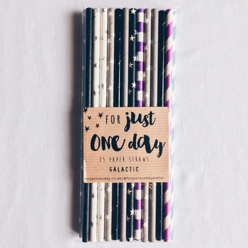 May include: A pack of 25 paper straws with a variety of patterns, including black and white stars, purple stripes, and gray stripes. The pack is labeled "For just one day 25 paper straws Galactic forjustoneday.co.uk @forjustonedayatelier"