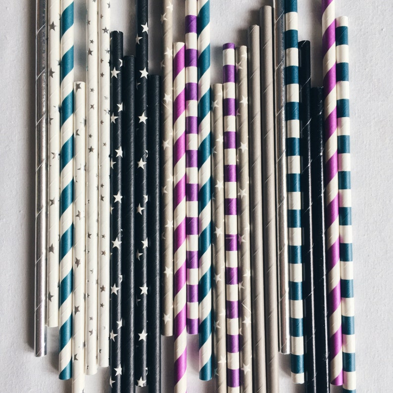 May include: A collection of colorful striped paper straws in various patterns, including black and white, blue and white, purple and white, and gray and white.