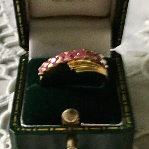 Peut inclure: Une bague en or avec une bande de pierres précieuses roses dans un écrin de velours vert.