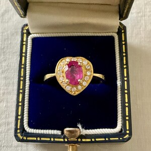 Peut inclure: Une bague en or avec un sertissage en forme de cœur présentant une pierre ovale rose entourée de petites pierres claires.