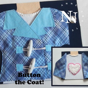 Peut inclure: Un manteau bleu et blanc à carreaux avec un col bleu et des boutons blancs. Le texte "Button the Coat!" est imprimé sous le manteau. Le manteau est ouvert pour révéler une chemise blanche avec un cœur rose.