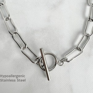 May include: A silver chain necklace with a toggle clasp. The chain is made of large, oval-shaped links. Hypoallergenic stainless steel.