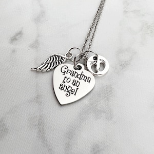May include: Silver necklace with a heart charm that says "Grandma to an angel" and a small charm with a footprint design. The necklace also has a small angel wing charm.