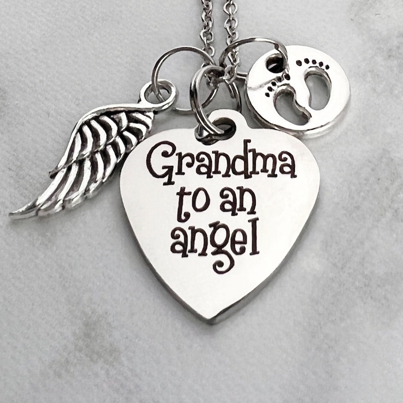 May include: Silver necklace with a heart charm that says "Grandma to an angel", a small angel wing charm, and a charm with a footprint design.
