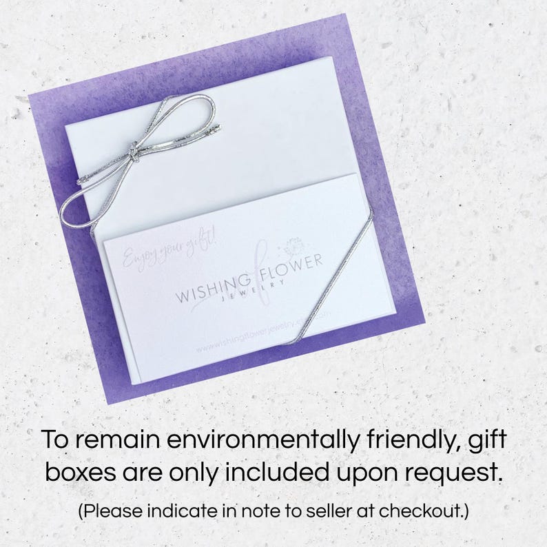 May include: A white gift box with a silver ribbon, a card with the text "Enjoy your gift!" and the "Wishing Flower Jewelry" logo, and a purple background. The text at the bottom says gift boxes are only included upon request.
