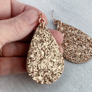 May include: Gold glitter teardrop earrings with a gold hook fastening.