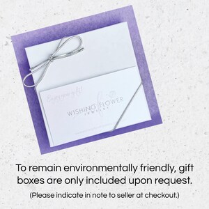 May include: A white gift box with a silver ribbon tied in a bow. The box has a white card on top with the text "Enjoy your gift!" and the logo "Wishing Flower Jewelry". The text "To remain environmentally friendly, gift boxes are only included upon request. (Please indicate in note to seller at checkout.)" is below the image.