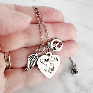 May include: Silver necklace with a heart charm that says "Grandma to an angel" and a small angel wing charm. The necklace also has a small charm with a footprint design.