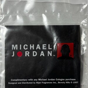 May include: A black card with the words "MICHAEL JORDAN" in white, a red dot, and a red square with a silhouette. The card is in a clear plastic bag. Text at the bottom reads "Complimentary with any Michael Jordan Cologne purchase."