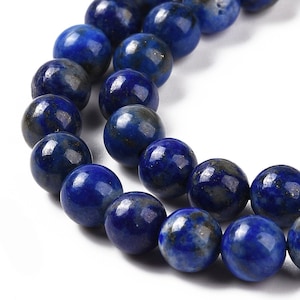 Peut inclure: Un brin de perles de lapis-lazuli bleu foncé avec des reflets dorés. Les perles sont rondes et lisses, et elles sont enfilées sur un fil transparent.