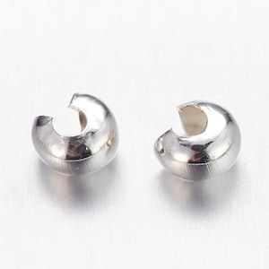 Peut inclure: Deux fermoirs de bijoux argentés en forme de C brillants. Les fermoirs ont un extérieur lisse et arrondi et un intérieur creux. Ils sont conçus pour connecter les extrémités d'un collier ou d'un bracelet.