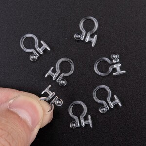 Peut inclure: Un ensemble de huit dos d'oreille en plastique transparent. Les dos sont conçus pour maintenir les boucles d'oreilles en place et sont idéaux pour les personnes ayant les oreilles sensibles.