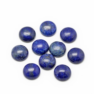 Peut inclure: Collection de neuf pierres de lapis-lazuli polies et rondes. Les pierres sont d'un bleu profond avec des éclats d'or et d'autres minéraux. Elles sont disposées sur un fond blanc.