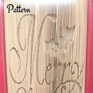 May include: A book with the words "Merry Christmas" folded into the pages. The book is bound in red and has a white spine. The text "Pattern" is visible at the top of the book.