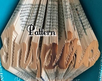 May include: A book art sculpture of the word "Movie" folded from the pages of a book. The book is bound in a teal blue cover with a white floral pattern. The sculpture is displayed on a beige surface.
