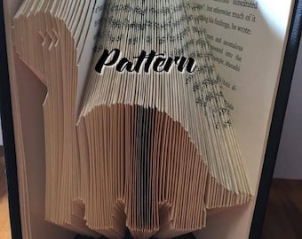 May include: A book art sculpture, also known as a book folding, in the shape of a pattern. The book is open and the pages are folded to create the pattern. The book is sitting on a wooden surface. The text "Premade Re Made" is visible on the bottom of the book.