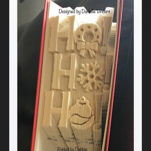 May include: A book with the word "Home" folded into the pages, along with a snowflake and a snowman. The book is red and has the text "Designed by Danielle Vincent" and "Folded by Debbie" on the cover.