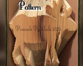 May include: A book transformed into a deer sculpture. The pages are intricately folded and cut to form the shape of a deer. The word "Pattern" is visible on the book's pages. The book's cover is green with a brown interior.