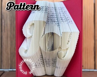 May include: A red book with the word "Pattern" in bold black letters on the front cover. The book is folded into the shape of the word "Joy" in white paper.