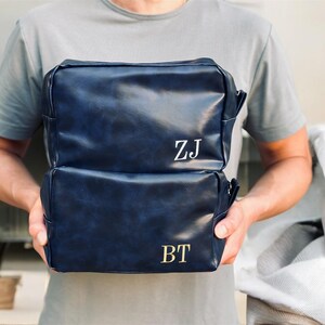 May include: Two blue leather zippered travel bags with gold initials "ZJ" and "BT" on the front.