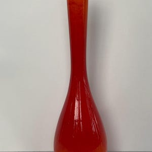 May include: A tall, slender vase with a vibrant gradient of colors. The base transitions from a warm orange to a rich red at the top. The vase has a smooth, glossy finish, and is suitable for home decor.
