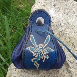 Può includere: Una piccola borsa in pelle blu con chiusura a coulisse. La borsa presenta un design in rilievo dettagliato di una fata con le ali.