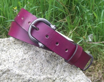 May include: A burgundy leather belt with a silver buckle. The belt is folded in half and lying on a rock.