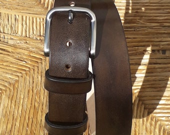 May include: A brown leather belt with a silver buckle. The belt is folded in half and the buckle is visible.