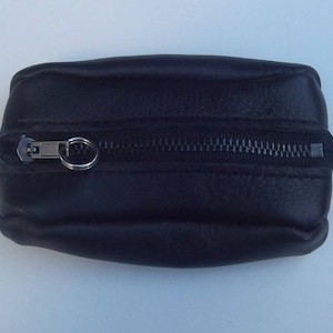 Può includere: Una piccola borsa in pelle nera con cerniera.