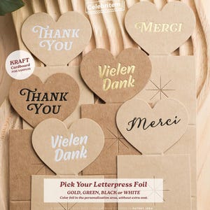 May include: Kraft cardboard heart-shaped samples with foil lettering. The hearts say "Thank You", "Merci", and "Vielen Dank" in various fonts and colors. The text "Pick Your Letterpress Foil" is also visible.