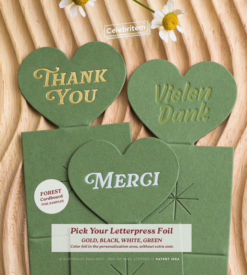 May include: Green heart-shaped cards with gold, white, and green foil lettering. The cards say "Thank You", "Vielen Dank", and "Merci". The cards are on a wooden surface with a daisy and the text "Pick Your Letterpress Foil".