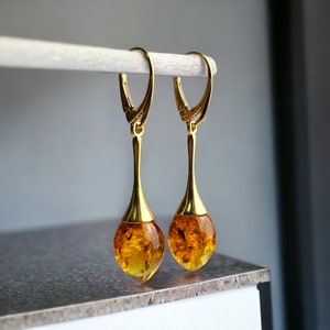 Puede incluir: Un par de pendientes de oro con piedras de ámbar en forma de lágrima.