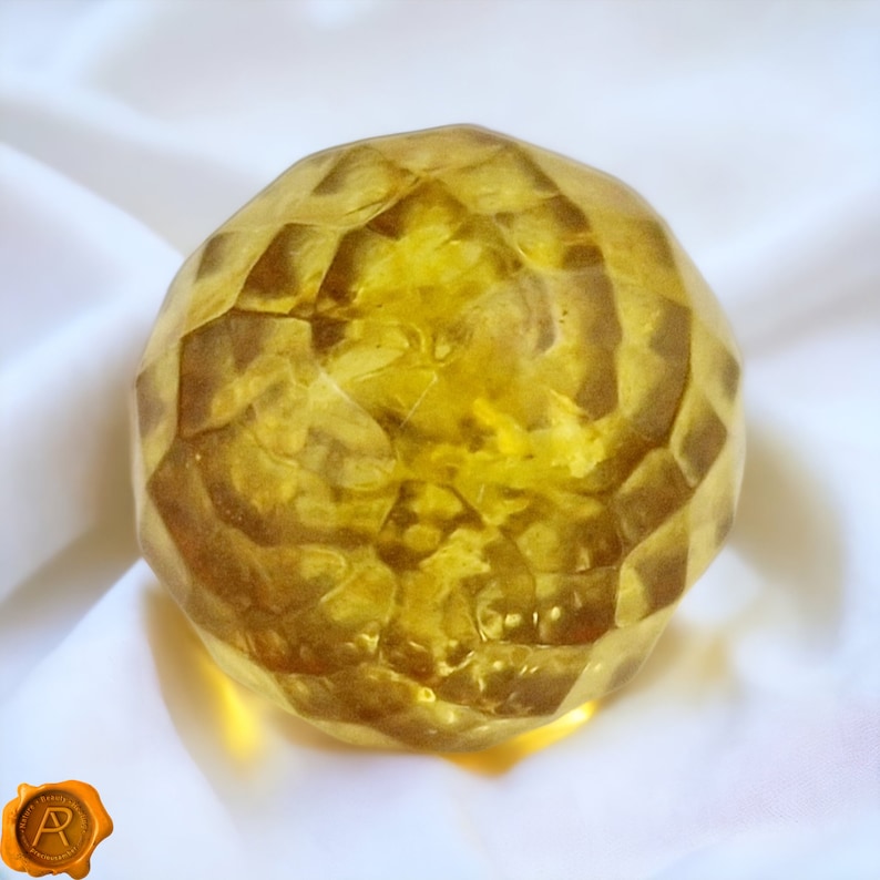 Pu&ograve; includere: Una grande sfera di vetro sfaccettata di colore ambrato. La sfera &egrave; liscia e lucida, con un aspetto leggermente nuvoloso.