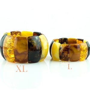 Puede incluir: Dos pulseras de ámbar, una etiquetada como "XL" y la otra como "L". Las pulseras están hechas de múltiples piezas de ámbar en diferentes tonos de amarillo, marrón y negro.