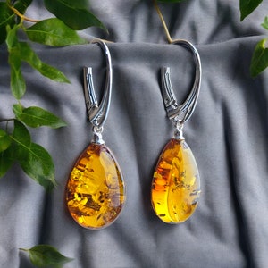 Op de afbeelding: Een paar amber druppel oorbellen met zilveren haken. De amber is een warme, honingkleur en heeft een natuurlijke, organische uitstraling. De oorbellen zijn een klassiek en elegant ontwerp.