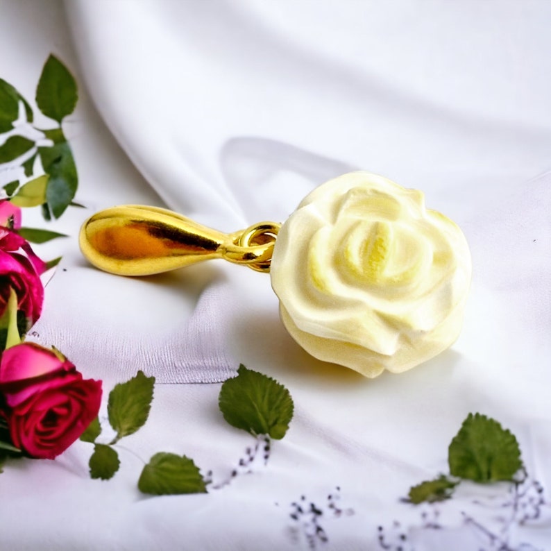 May include: A gold-colored bottle stopper with a white rose design. The rose is detailed and realistic, with a textured surface.
