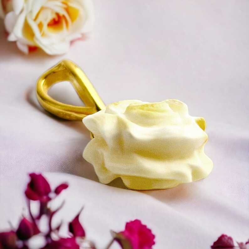 May include: A gold pendant featuring a white, sculpted rose. The pendant is on a white background.