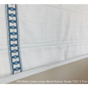 May include: Off white cotton linen blend Roman shade with a blue geometric pattern trim. The shade is partially rolled up, showing the fabric texture. The text "Off White Cotton Linen Blend Roman Shade 7207-5 Trim" is visible at the bottom of the image.