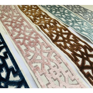 May include: Five different trims with a geometric pattern. The trims are in shades of blue, pink, brown, and gray. The trims are all on a white background.