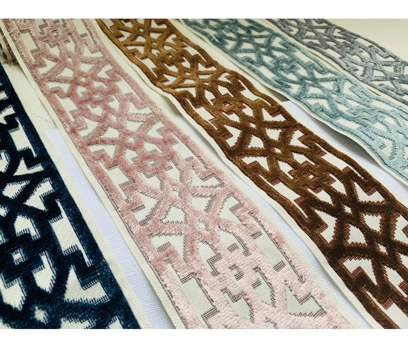 May include: Five different trims with a geometric pattern. The trims are in shades of blue, pink, brown, and gray. The trims are all on a white background.
