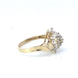 May include: A gold ring with a cluster of small diamonds set in a flower-like design. The ring is marked "10K 141".