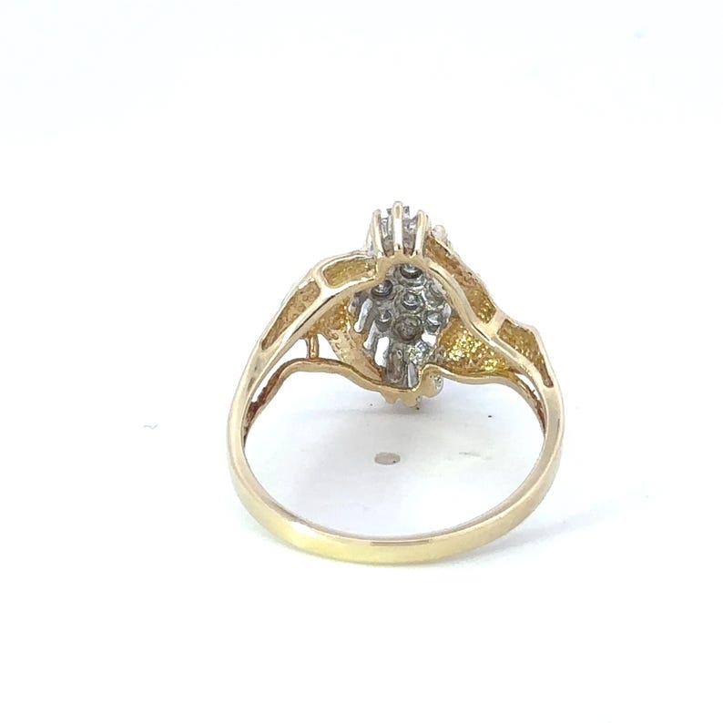 May include: A gold ring with a cluster of small diamonds set in a floral design.