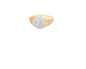 May include: A gold ring with a cluster of small, round, clear stones set in a circular design. The band has a brushed, matte finish, and the ring is set against a white background.